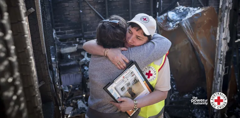 Australian Red Cross volunteer comforting a survivor amid bushfire damage