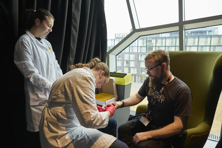 A capsuleer donates blood for the Capsuleer Edda heritage project at EVE Fanfest 2026 - blood mixed into the ink that records the poem of New Eden