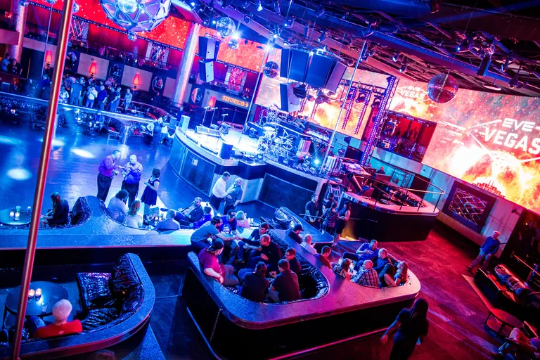 Capsuleers gathered at the EVE Vegas 2017 venue, tables beneath the event's EVE Vegas stage screens